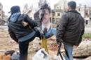 FILE - In this Tuesday, March. 20, 2012 file citizen journalism image provided by the Local Coordination Committees in Syria and accessed on Wednesday, March 21, 2012, Syrian rebels step on a portrait of Syrian President Bashar Assad in Idlib province, Syria. It began in March 2011 with a few words spray-painted on a schoolyard wall: 