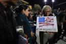 A woman with a sign showing the American flag made of guns attends a candlelight vigil at the San Manuel Stadium in San Bernardino, California, December 3, 2015 for victims of the shooting that left 14 dead and at least 17 injured