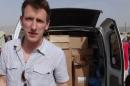 FILE - In this undated file photo provided by his family, Peter Kassig stands in front of a truck filled with supplies for Syrian refugees. The Indianapolis, Indiana, aid worker being held by the Islamic State group told family and teachers that he'd found his calling in 2012 when he decided to stay in the Middle East instead of returning to college, according to an email released Tuesday, Oct. 14, 2014 by his family. (AP Photo/Courtesy Kassig Family, File)