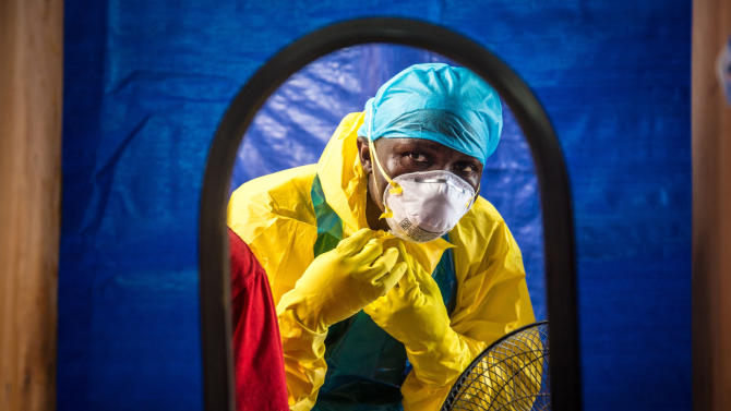 In this Thursday, Oct. 16, 2014 file photo, a healthcare worker dons protective gear before entering an Ebola treatment center in the west of Freetown, Sierra Leone.  Dr. Brima Kargbo, Sierra Leone's chief medical officer, confirmed Thursday Dec. 18, 2014, that Dr. Victor Willoughby died earlier in the day after being tested positive for Ebola on Saturday, the 11th doctor in the country to die from the disease that is ravaging West Africa. (AP Photo/Michael Duff, FILE)
