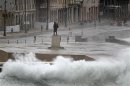Waves crash against Havana's seafront boulevard 'El Malecon' as tourists take pictures