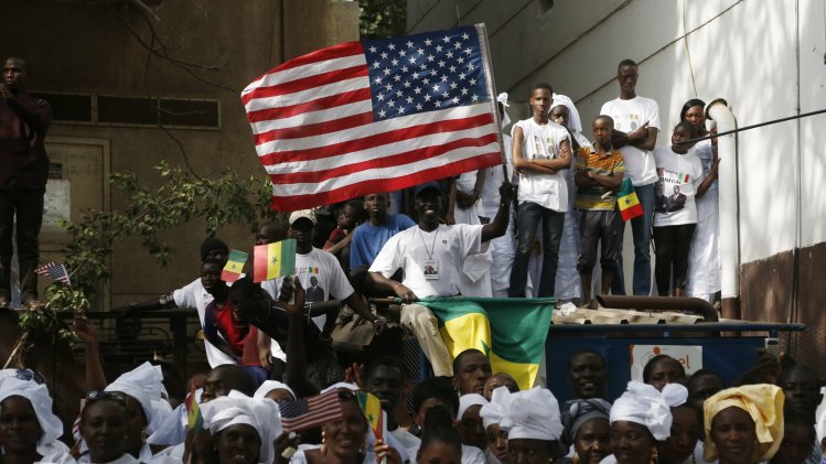 Senegalese watch as U.S. President Obama's motorcade drives past on his way to meet with Senegal's President Sall at the Presidential Palace in Dakar