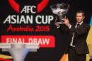 Australian soccer player Brett Emerton raises the trophy before the Asian Football Confederation draw for the 2015 Asian Cup at the Sydney Opera House ground in Sydney, Wednesday, March 26, 2014. Australia hosts the tournament that will be played in Jan. 2015. (AP Photo/Rick Rycroft)