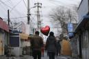 A woman holding a heart-shaped balloon walks with her partner at a residential area for migrant workers on Valentine's Day in Beijing