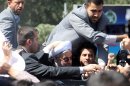 Iranian president Hassan Rouhani is protected by bodyguards as his motorcade draw out of Tehran's Mehrabad Airport upon his arrival from New York, on September 28, 2013