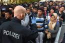 A German police officer speaks with migrants waiting to cross the Austrian-German border near the Bavarian town of Passau, southern Germany, on October 28, 2015