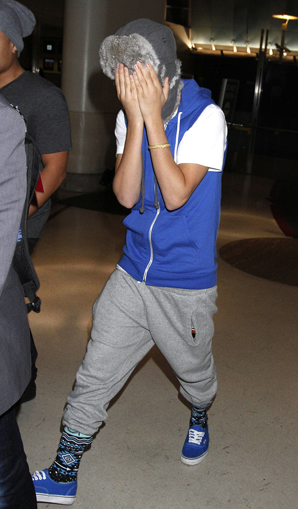 Justin Bieber playfully covers his face wearing matching blue vest & shoes and in sweats as he makes his way through LAX.