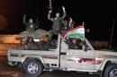 Kurdish peshmerga fighters wave a Kurdish flag from a military vehicle armed with a heavy infantry weapons as they ride towards the Syrian town of Kobane from the border town of Suruc, Turkey, October 31, 2014