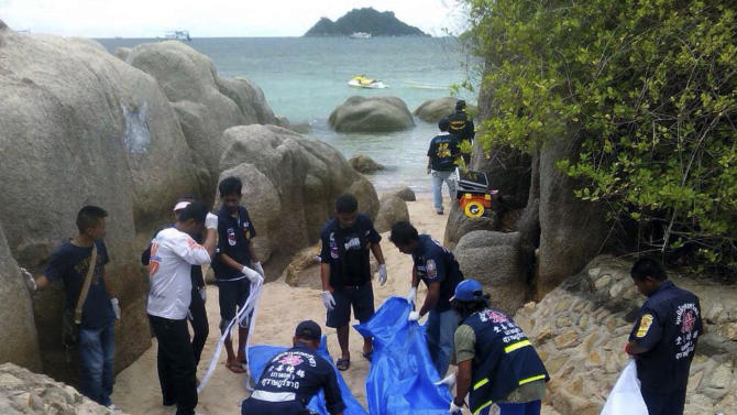 Thai officers work near the bodies of two British tourists Monday, Sept. 15, 2014 on a beach in Surat Thani  province, southern Thailand. Their bodies were discovered early Monday on a beach on Koh Tao, a small island known for its diving sites and serene beaches, police said. (AP Photo/Daily News) THAILAND OUT