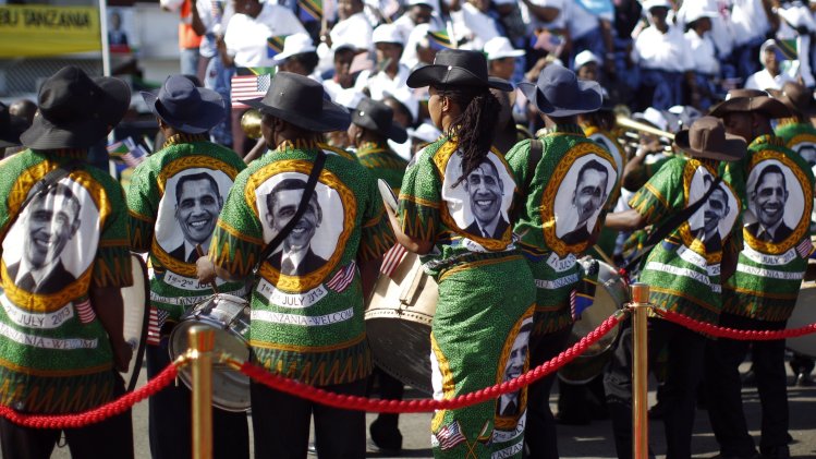 Members of a Tanzanian band wear outfits featuring an image of U.S. President Barack Obama at an official arrival ceremony at Julius Nyerere Airport in Dar es Salaam