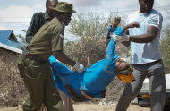 Members of the Kenyan security forces remove the body of a woman killed in the attack at the African Inland Church in Garissa, Kenya Sunday, July 1, 2012. Grenade and gunfire attacks on two Kenyan churches near the border with Somalia killed 10 people and wounded 40 on Sunday in what was likely an attack by militants from Somalia, an official said. (AP Photo/Chris Mann)