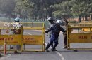 A member of the Rapid Action Force pulls a barricade to close a road leading to the India Gate in New Delhi