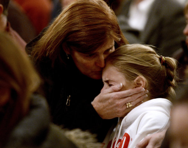 A woman comforts a young girl during a vigil service for victims of the Sandy Hook Elementary shooting, Friday, Dec. 14, 2012, at St. Rose of Lima Roman Catholic Church in Newtown, Conn. (AP Photo/Andrew Gombert, Pool)