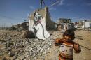 Palestinian girl looks on as a mural of a playful-looking kitten, presumably painted by British street artist Banksy, is seen on the remains of a house wall, in Biet Hano