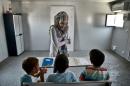 A teacher gives English lessons to children in a container converted into a classroom on June 24, 2016 at the refugee camp of Skaramangs, south of Athens