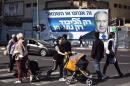 Pedestrians cross a street in front of a campaign billboard depicting Israeli Prime Minister Netanyahu in Ramat Gan