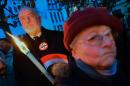 A protestor (L) wearing a button with a crossed-out swastika holds a torch in the town of Szekesfehervar, Hungary on December 13, 2015 at a rally against a planned statue of World War II politician Balint Homan, an architect of anti-Jewish laws