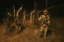 Indian BSF soldiers walk during night patrol near the fenced border with Pakistan in Abdullian