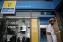 A man leaves an ATM of a Hellenic Post bank branch in Athens