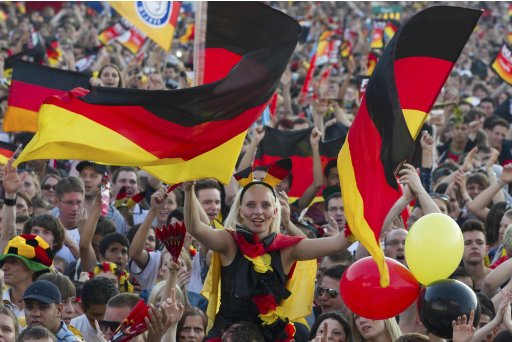 Germany supporters wave flags as they watch Germany plays Portugal during Euro 2012 soccer match at the Fan Mile in Berlin