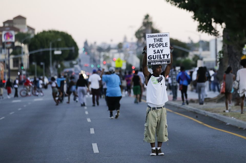 A protester holds up a sign while marching down the street during a demonstration in reaction to the acquittal of neighborhood watch volunteer George Zimmerman on Monday, July 15, 2013, in Los Angeles. Anger over the acquittal of a U.S. neighborhood watch volunteer who shot dead an unarmed black teenager continued Monday, with civil rights leaders saying mostly peaceful protests will continue this weekend with vigils in dozens of cities. (AP Photo/Jae C. Hong)
