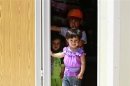Syrian refugee children stand inside their family caravan at the Mrajeeb Al Fhood refugee camp