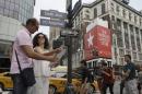 Newlyweds Valasia Limnioti, right, and Konstantinos Patronis stand along 34th Street and 6th Avenue in Midtown Manhattan, Thursday, July 2, 2015, in New York. Newlyweds Limnioti and Patronis topped "the dream trip of our lives" in New York City, where their three-week honeymoon turned into a nightmare: Their Greek-issued credit cards were suddenly declined and they were left nearly penniless. Strangers from two Greek Orthodox churches in Queens came to their rescue, giving them survival cash until their flight home to Greece this Friday. (AP Photo/Mary Altaffer)