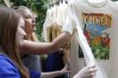 Women inspect T-shirts, displaying images of Russia's President Vladimir Putin, which are on sale at GUM department store in central Moscow