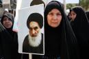 An Iraqi woman living in Iran holds a poster of the Grand Ayatollah Ali al-Sistani, Iraq's top Shiite cleric, in a demonstration against Sunni militants of the al-Qaida-inspired Islamic State of Iraq and the Levant, or ISIL, and to support Ayatollah al-Sistani, in Tehran, Iran, Friday, June 20, 2014. (AP Photo/Ebrahim Noroozi)