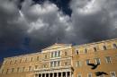 A Greek national flag flutters atop the parliament building in Athens