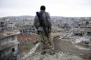 FILE - In this Jan. 30, 2015 file photo, a Syrian Kurdish sniper looks at the rubble in the Syrian city of Ain al-Arab, also known as Kobani. Foreign fighters are streaming in unprecedented numbers to Syria and Iraq to battle for the Islamic State or other U.S. foes, including at least 3,400 from Western nations and 150 Americans, U.S. intelligence officials conclude. In all, more than 20,000 fighters have traveled to Syria from more than 90 countries, top intelligence officials will tell Congress this week. (AP Photo, File)