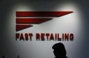 An employee of Fast Retailing Co is silhouetted in front of its logo at its headquarters in Tokyo
