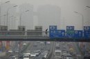 A pedestrian walks across a bridge above a main road on a day with high air pollution in Beijing