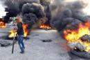 A protestor walks in front of burning tyres as they block a street in Libya's second city of Benghazi on February 26, 2014