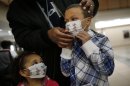 Here Damien Dancy puts masks on his children Damaya, 3, left, and Damien, 7, on Wednesday, Jan. 9, 2013 at Sentara Princess Anne Hospital in Virginia Beach, Va. Hospitals in Hampton Roads are urging patients and visitors to wear a mask at their facilities to help stop the spread of the flu. The recommendation was issued Wednesday by more than two dozen medical centers. In a joint statement, the hospitals said the recommendation applies to hospitals, urgent care centers and branch clinics, among others. (AP Photo/The Virginian-Pilot, Stephen M. Katz)