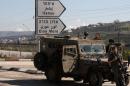 Israeli soldiers stand guard at a road leading to the Itamar settlement near the West Bank city of Nablus on March 12, 2011