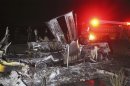 A fire truck stands near the burnt remains of a delivery truck on a road on the outskirts of Morelia