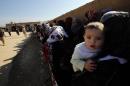 A Syrian woman holds her child in the queue with families who fled recent violence in the mountainous Qalamoun region, waiting to be registered by the United Nations High Commissioner for Refugees (UNHCR) in Arsal, Lebanon on November 19, 2013
