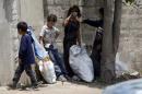Syrian refugee children collect plastics as they stand along a street in south of Sidon