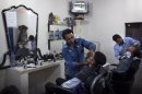 A Syrian barber gives a shave to a client at his shop at an industrial zone near Aleppo, on September 20, 2013