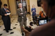 U.S. Representative Darrell Issa (R-CA) (left) reads notes about a possible deal in the Senate as he and Representative Peter Welch (D-VT) (center) stand for separate television interviews at the U.S. Capitol in Washington December 31, 2012. REUTERS/Jonathan Ernst