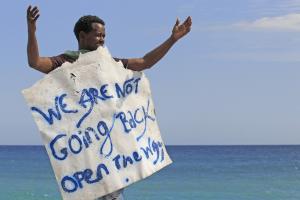 A migrant holds a sign reading &quot;we are not going&nbsp;&hellip;