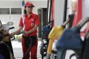 A petrol station attendant fills fuel into her customer's car at a petrol station in Jakarta
