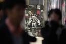 People walk past a sticker art made by an artist known as 281 Antinuke, designed in the likeness of Japan's Prime Minister Abe, along a street in Tokyo