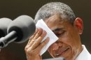 U.S. President Obama wipes his face while he speaks about his vision to reduce carbon pollution in Washington