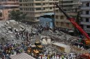 An aerial view shows bystanders watching rescuers search for survivors amongst the rubble of a collapsed building in the Kariakoo district of central Dar es Salaam