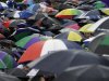 FILE - In this July 8, 2012 file photo, spectators take cover under umbrellas as they gather ahead of Andy Murray of Britain facing Roger Federer of Switzerland during the men's singles final match at the All England Lawn Tennis Championships at Wimbledon, England. Gold, silver, bronze: No matter who wins what at the London Olympics, a million or more visitors will need to get themselves an umbrella. (AP Photo/Alastair Grant, File)