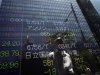 Man is reflected on electronic monitor displaying share prices outside a brokerage in Tokyo