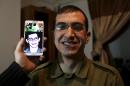 In this Sunday, Jan. 26, 2014 photo, director Majed Jundiyeh holds a mobile phone to compare the image of Gilad Schalit to the likeness of actor Mahmoud Karira, who will play the character of Shalit in a movie being made in Gaza called, ''Losing Shalit," in Gaza City. "Losing Schalit," currently being filmed in the blockaded territory, is the first of a planned three-part series about the 2006 capture of Israeli soldier Gilad Schalit by gunmen allied with the Islamic militant Hamas movement. Parts two and three will depict Schalit's time in captivity and his 2011 swap for hundreds of Palestinian prisoners held by Israel. (AP Photo/Hatem Moussa)