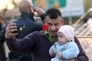 In this Saturday, Feb. 13, 2016 photo, an Iraqi man takes a photo with his child ahead of Valentine's Day at Zawra Park in Baghdad, Iraq. Baghdad is plastered with Valentine hearts and roses, and Iraqis are enjoying a rare lull in violence but wondering how long it will last. Despite recent setbacks, the Islamic State group is still dug in west of Baghdad, and increasingly powerful Shiite militias patrol the streets. (AP Photo/Hadi Mizban)